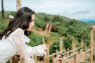 Melancholic Asian woman against green ridge in summer