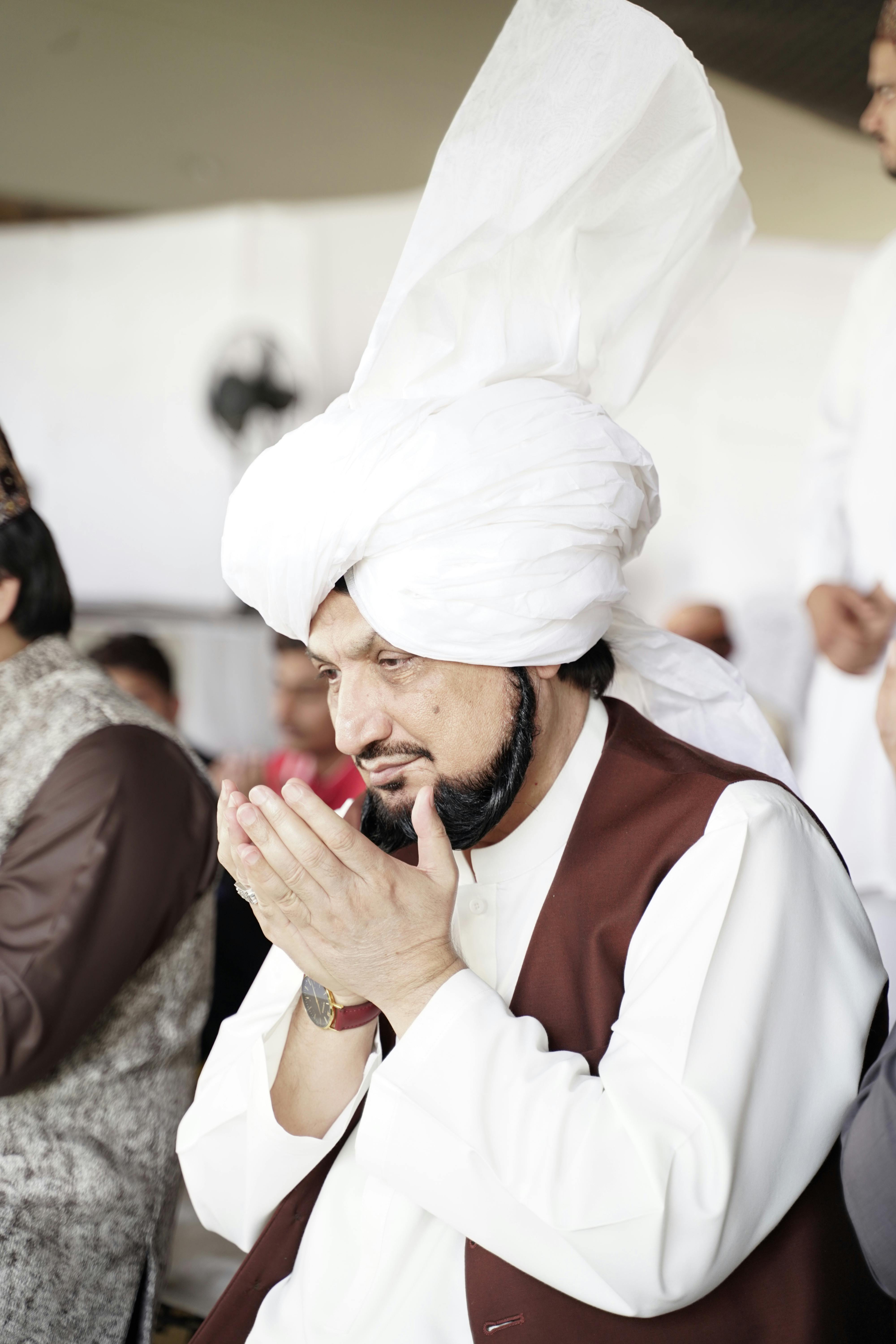A man with a turban praying during a religious ceremony in Pakistan.
