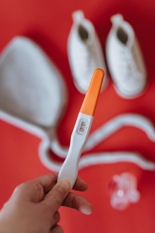 Person Holding Orange and White Pregnancy Test Tool