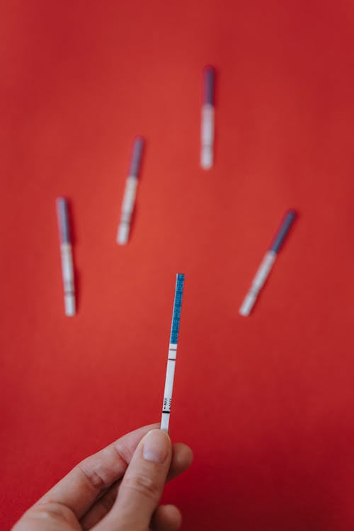 Close-Up Shot of a Person Holding a Positive Pregnancy Test Strip