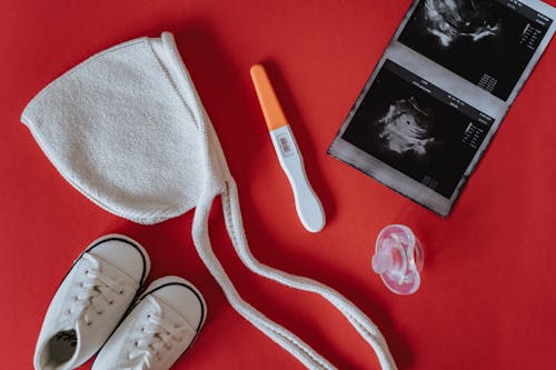 Close-Up Shot of Pregnancy Test Near Baby's Things