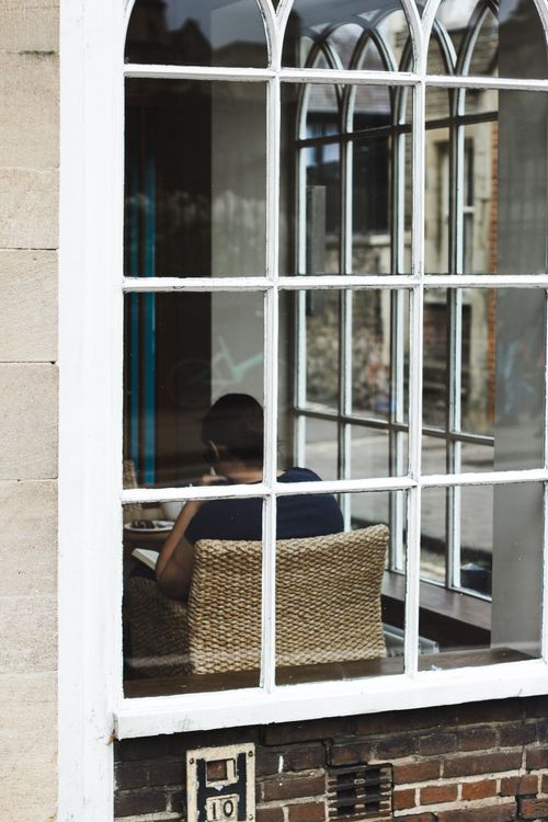 Free Through window anonymous person sitting on wicker chair in modern mansion lobby in daylight Stock Photo