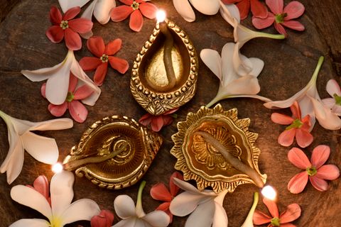 Three brass diyas among flowers