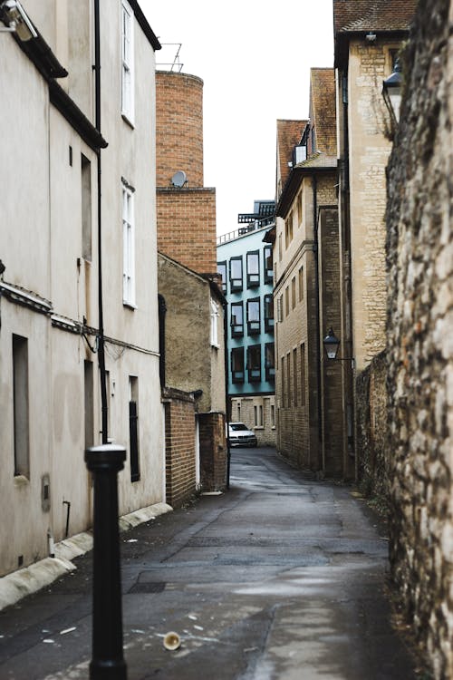 Narrow asphalt road running through old concrete buildings in residential city district on overcast day