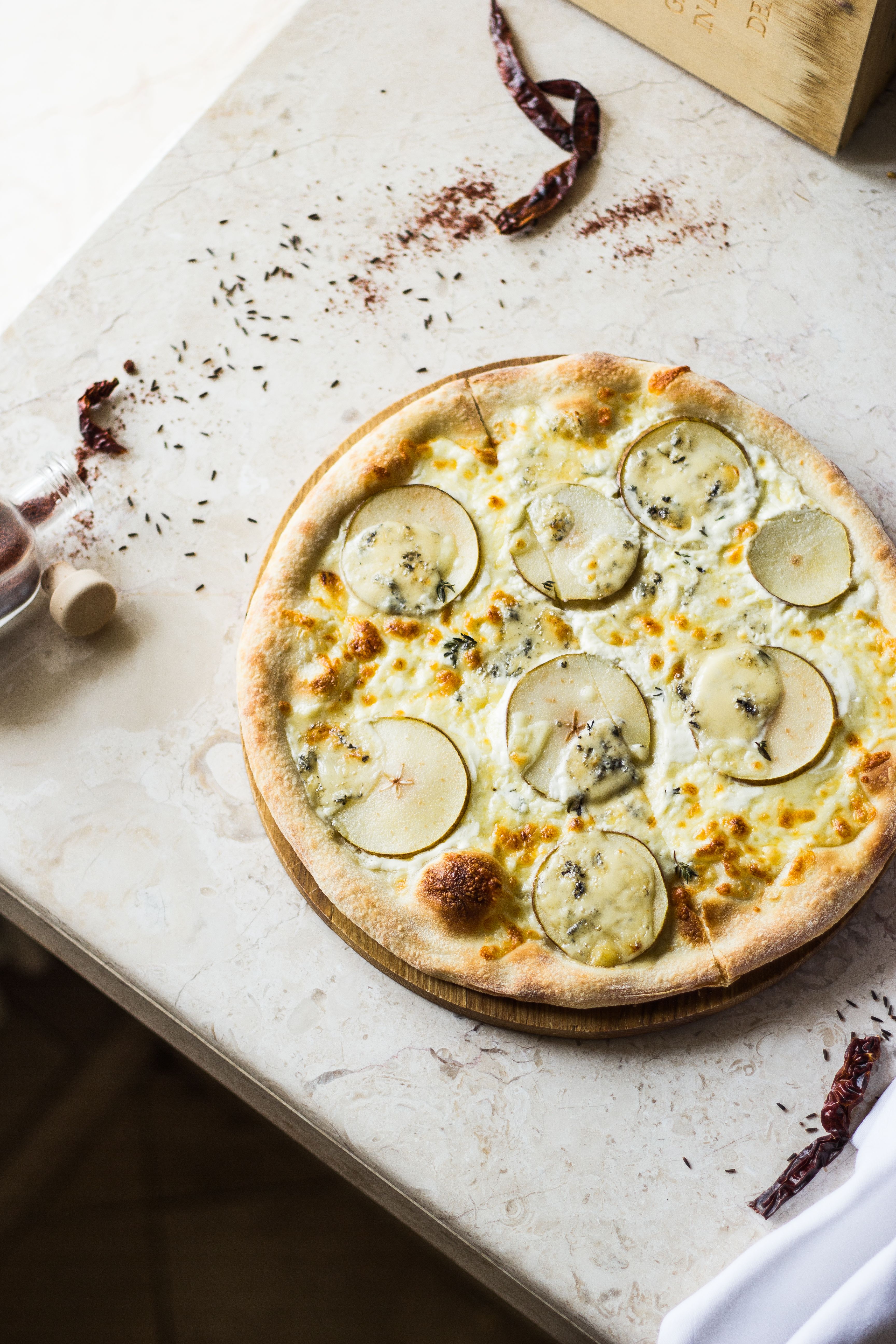 Close-up of artisanal potato and cheese pizza on a marble surface, showcasing gourmet ingredients.