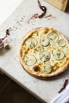 Close-up of artisanal potato and cheese pizza on a marble surface, showcasing gourmet ingredients.