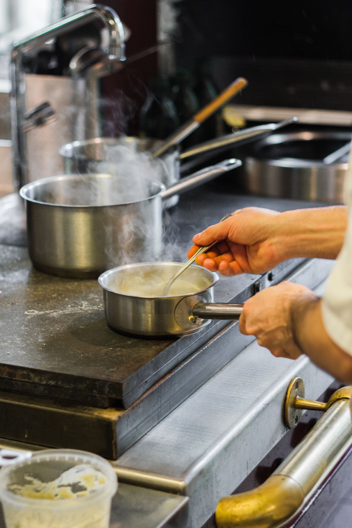 Hands finishing a sauce in a stainless pan