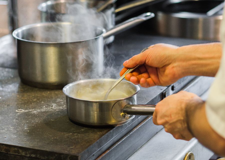 Koch rührt Sauce in der Profiküche