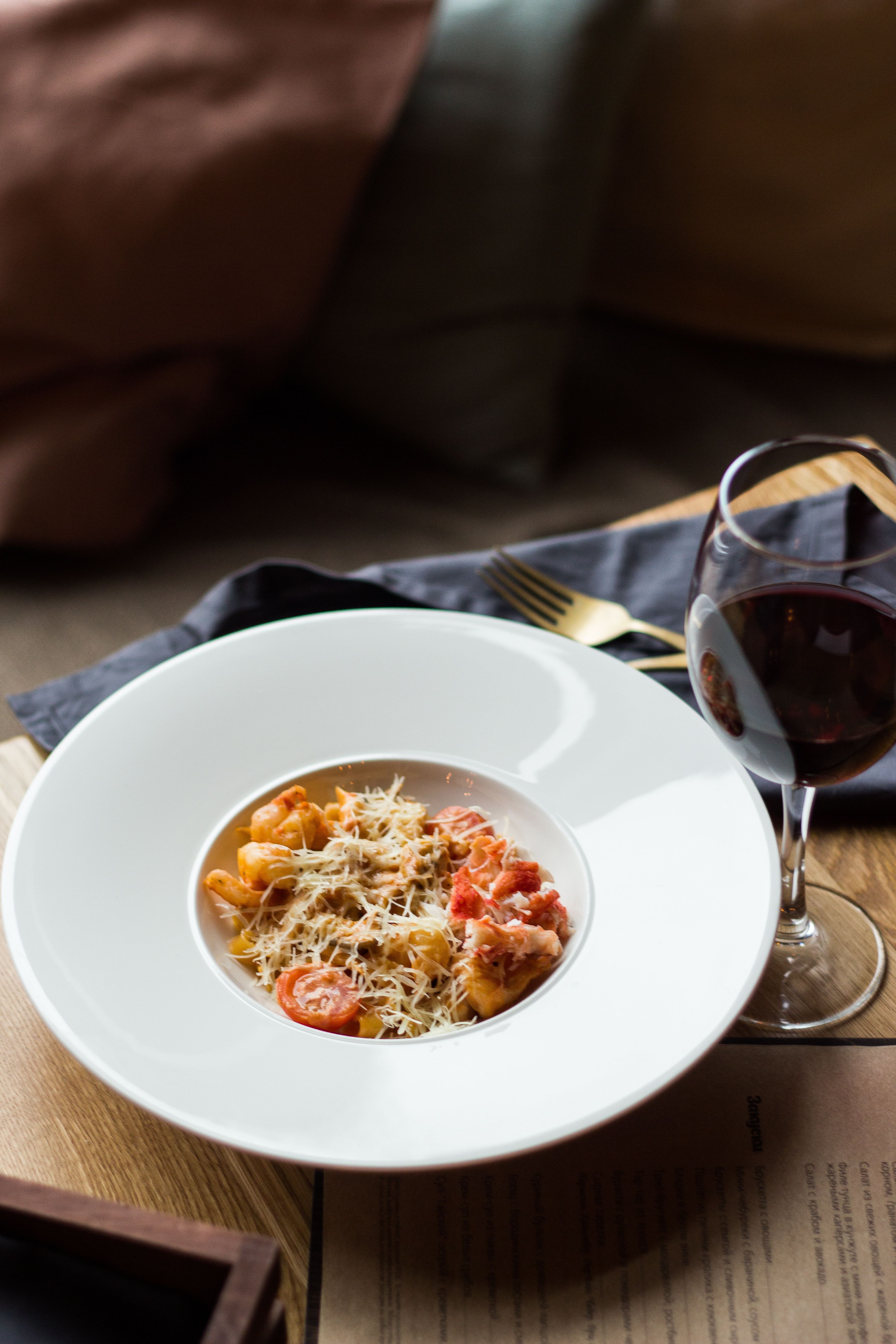 A delicious gourmet pasta dish served with red wine, set in a cozy indoor environment.