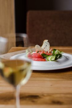 Close-up of a gourmet salad with wine glass on a table, perfect for elegant dining settings.