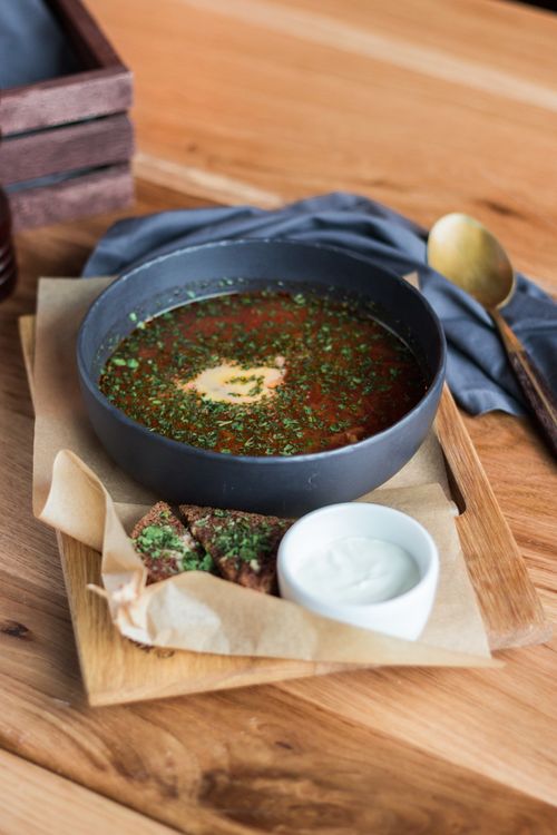 Free A delicious bowl of herb-infused soup served with bread and cream, perfect for a cozy meal. Stock Photo