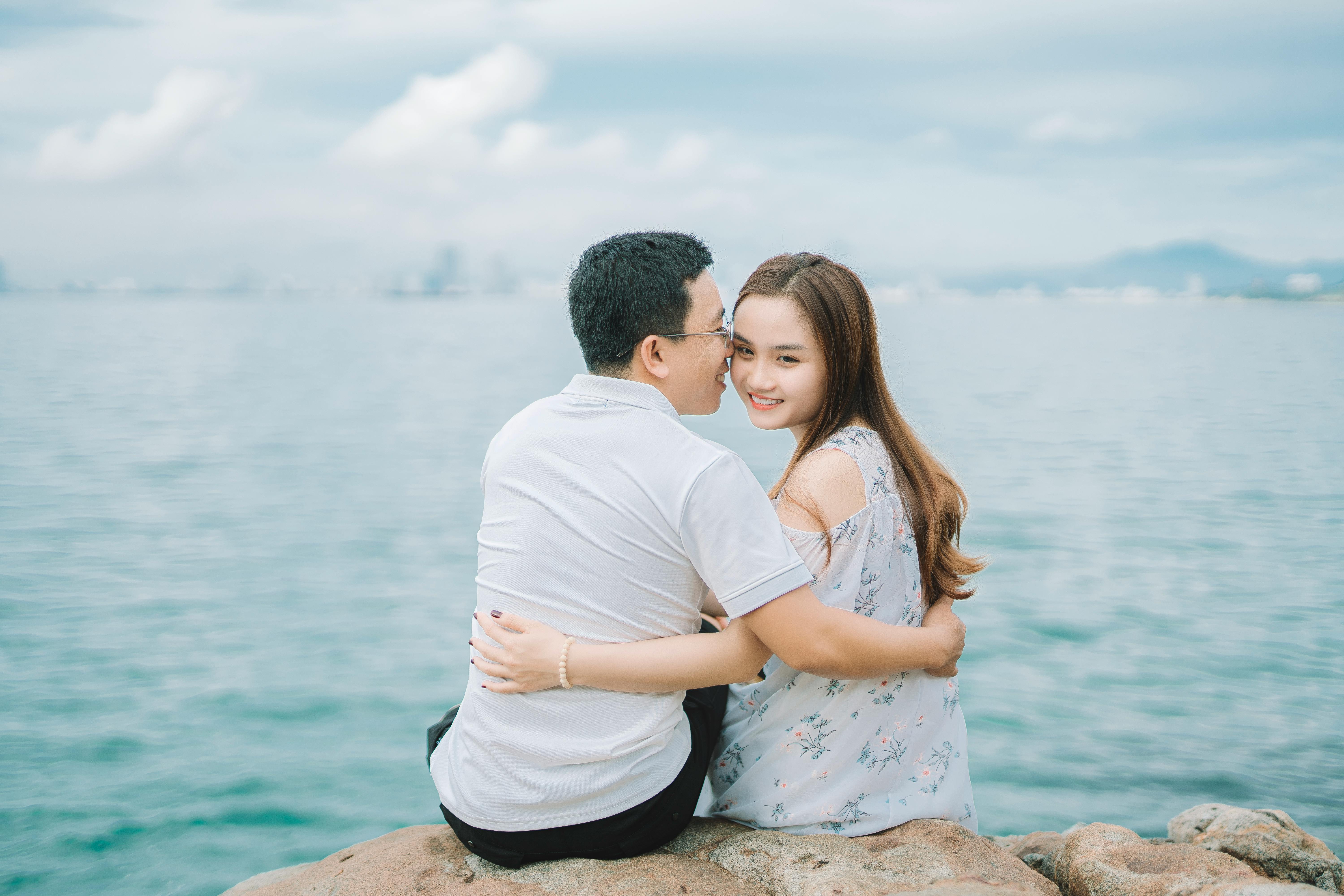 Gratis Hombre Y Mujer, Sentado, En, Roca, Cerca, Cuerpo De Agua Foto de stock