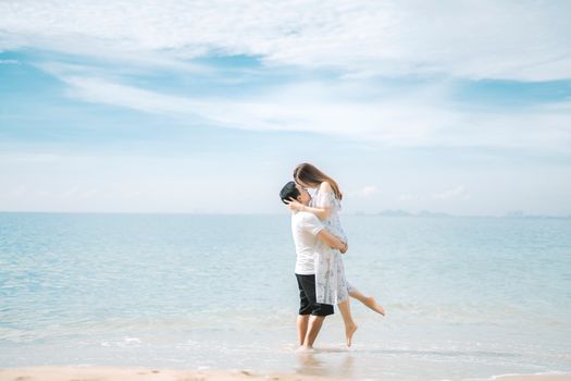 Anonymous couple embracing near ocean on sandy shore