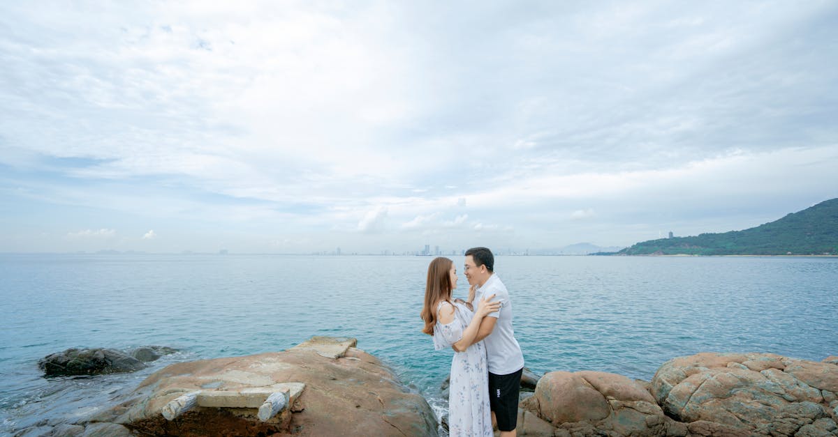 Couple hugging on rocky coast near ocean · Free Stock Photo