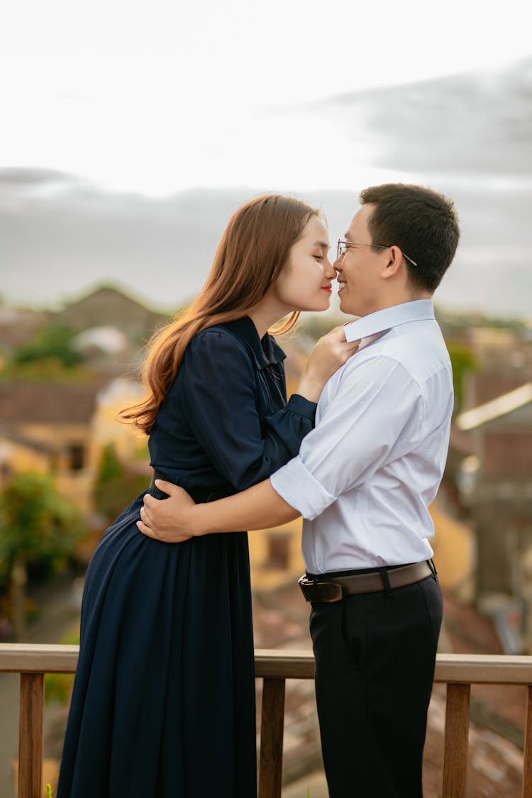 Smiling Asian Couple Hugging On Building Balcony In City