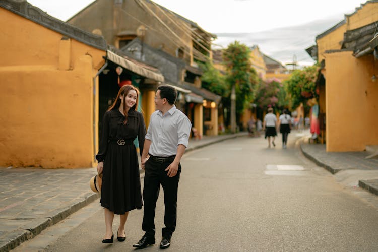 Content Asian Couple Talking While Walking On Road In Town