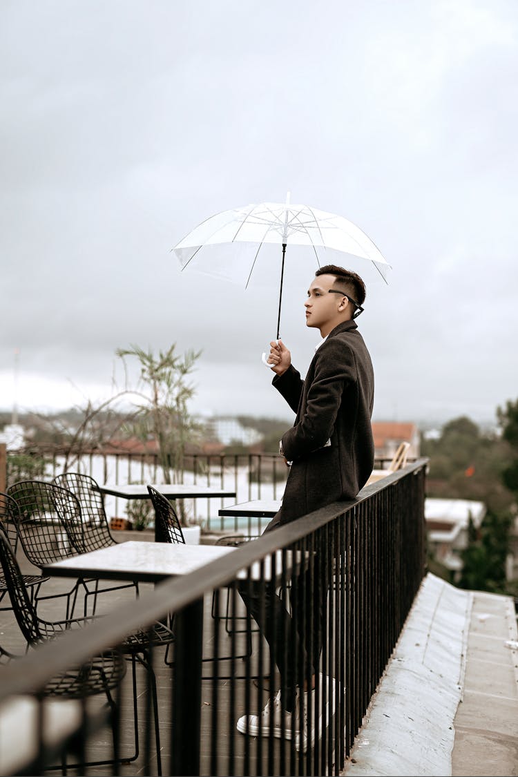 Stylish Ethnic Man With Umbrella On Terrace In Cafe