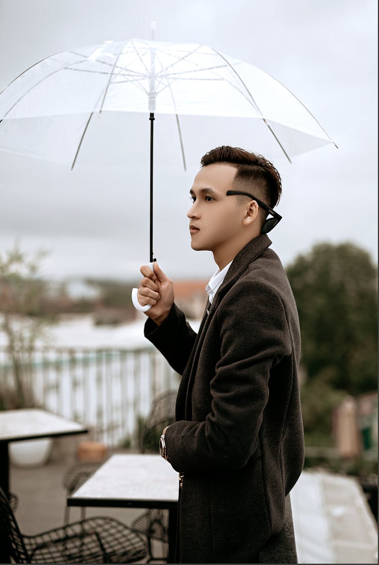 Pensive Ethnic Man In Stylish Coat With Umbrella In Cafe