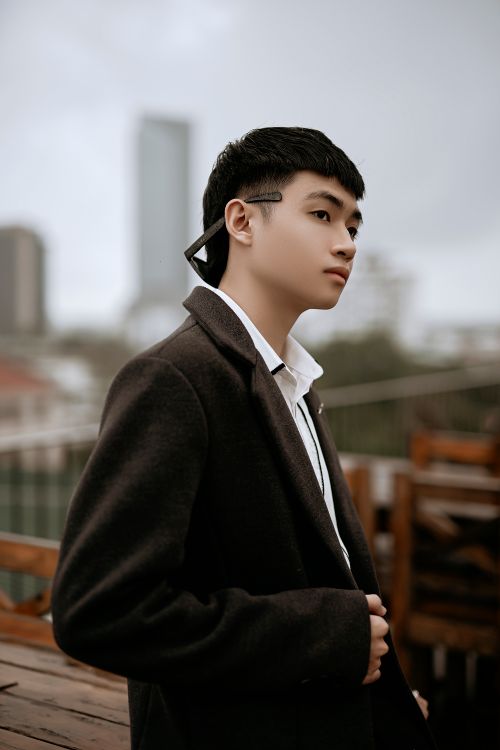 Free Side view of young pensive well dressed ethnic male in coat looking away in urban cafe Stock Photo