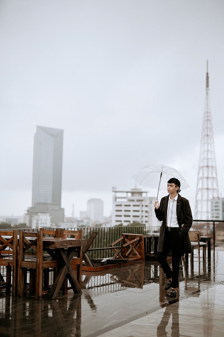 Stylish Asian Man With Umbrella On Urban Cafe Terrace