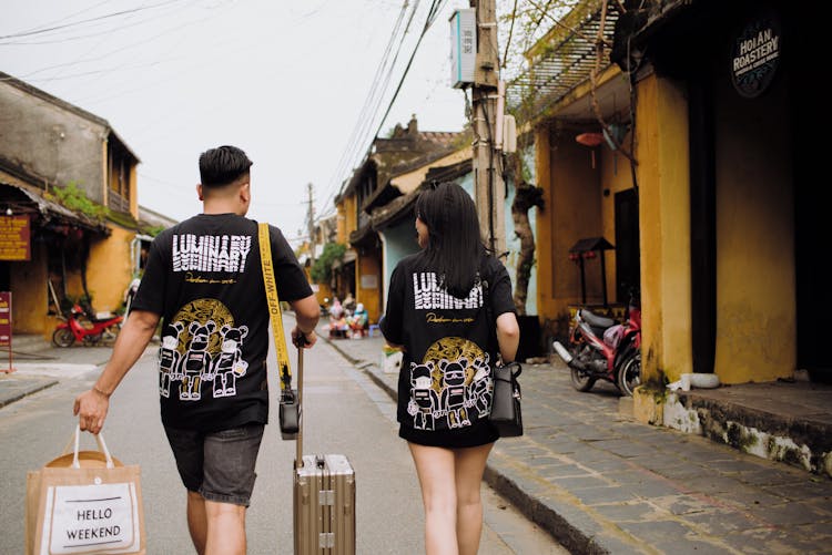 Unrecognizable Couple Of Travelers Walking On Urban Road