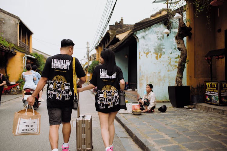 Unrecognizable Couple Of Travelers Walking On Urban Road