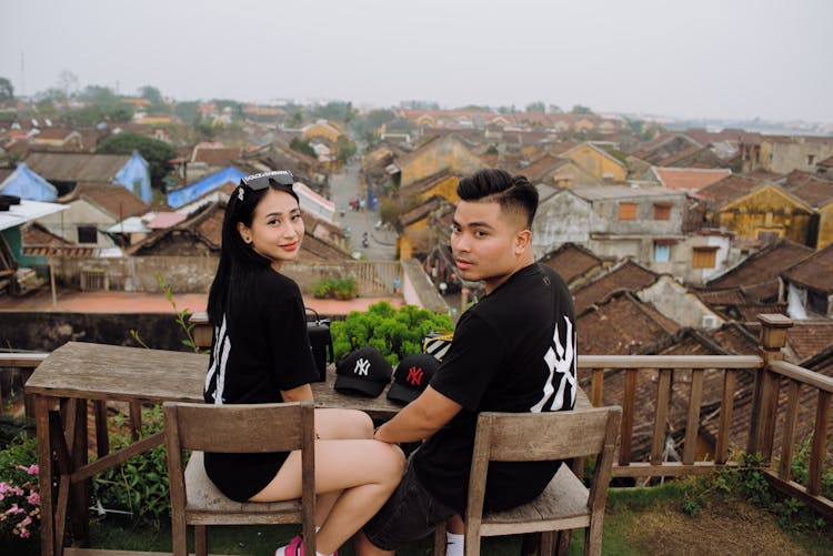 Asian Couple Of Travelers Resting At Table In Old Town