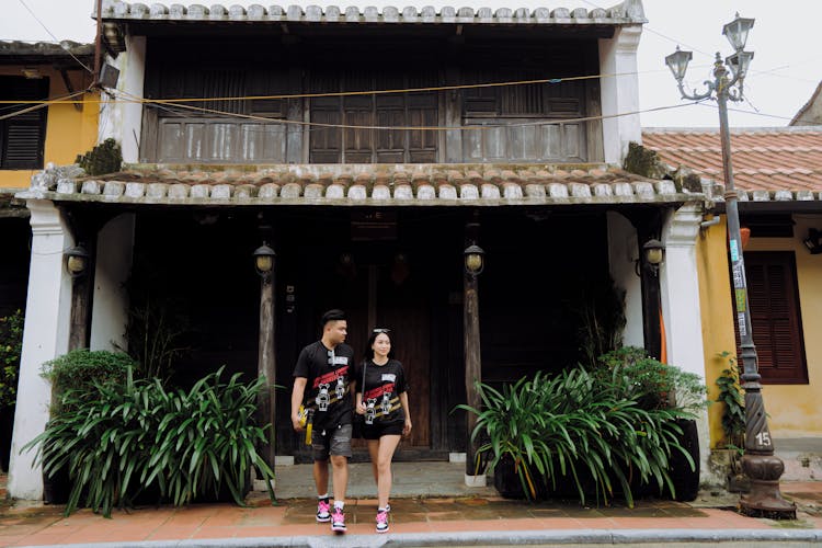 Asian Couple Leaving Wooden House Together