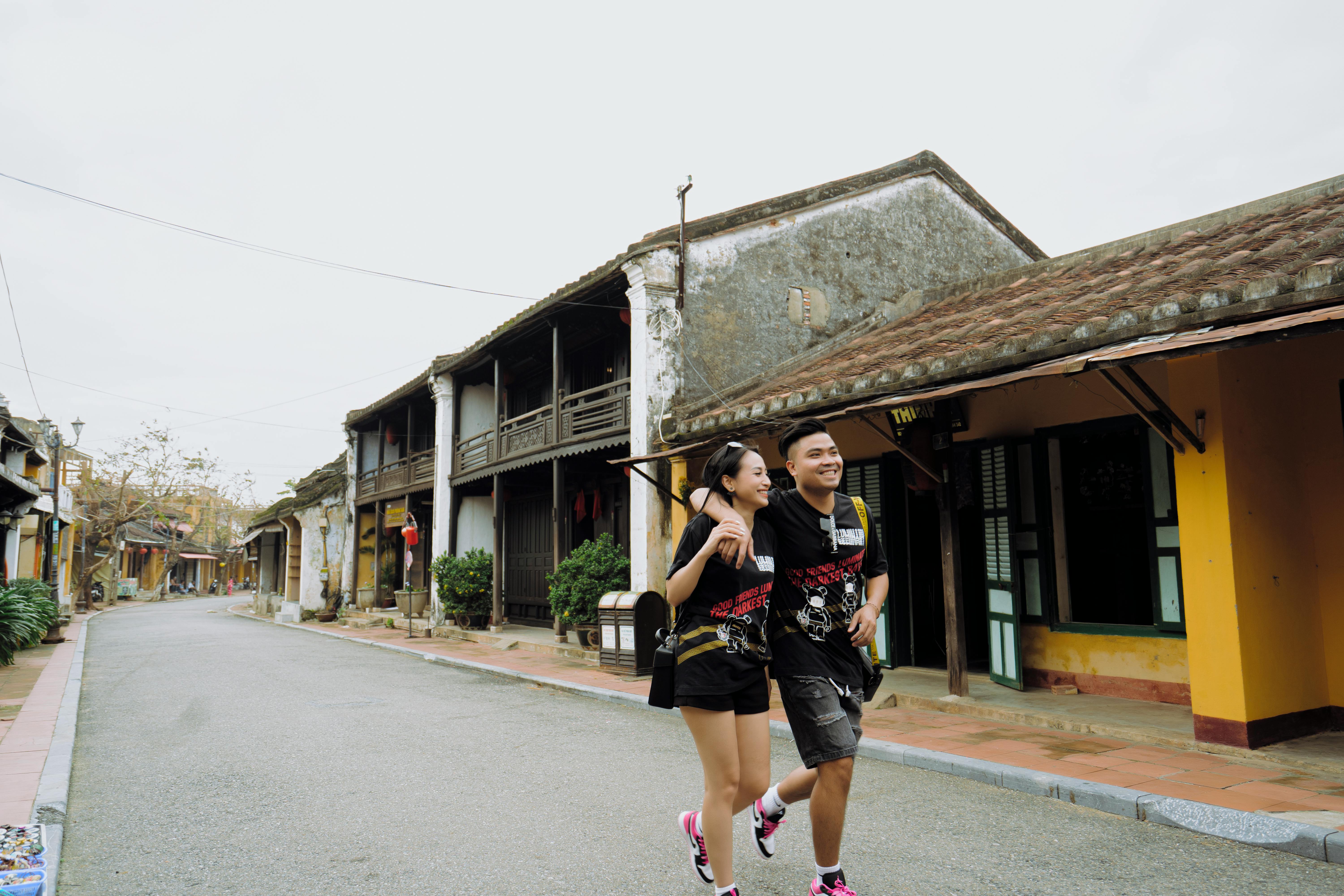 Joyful Asian couple embracing and walking on town street