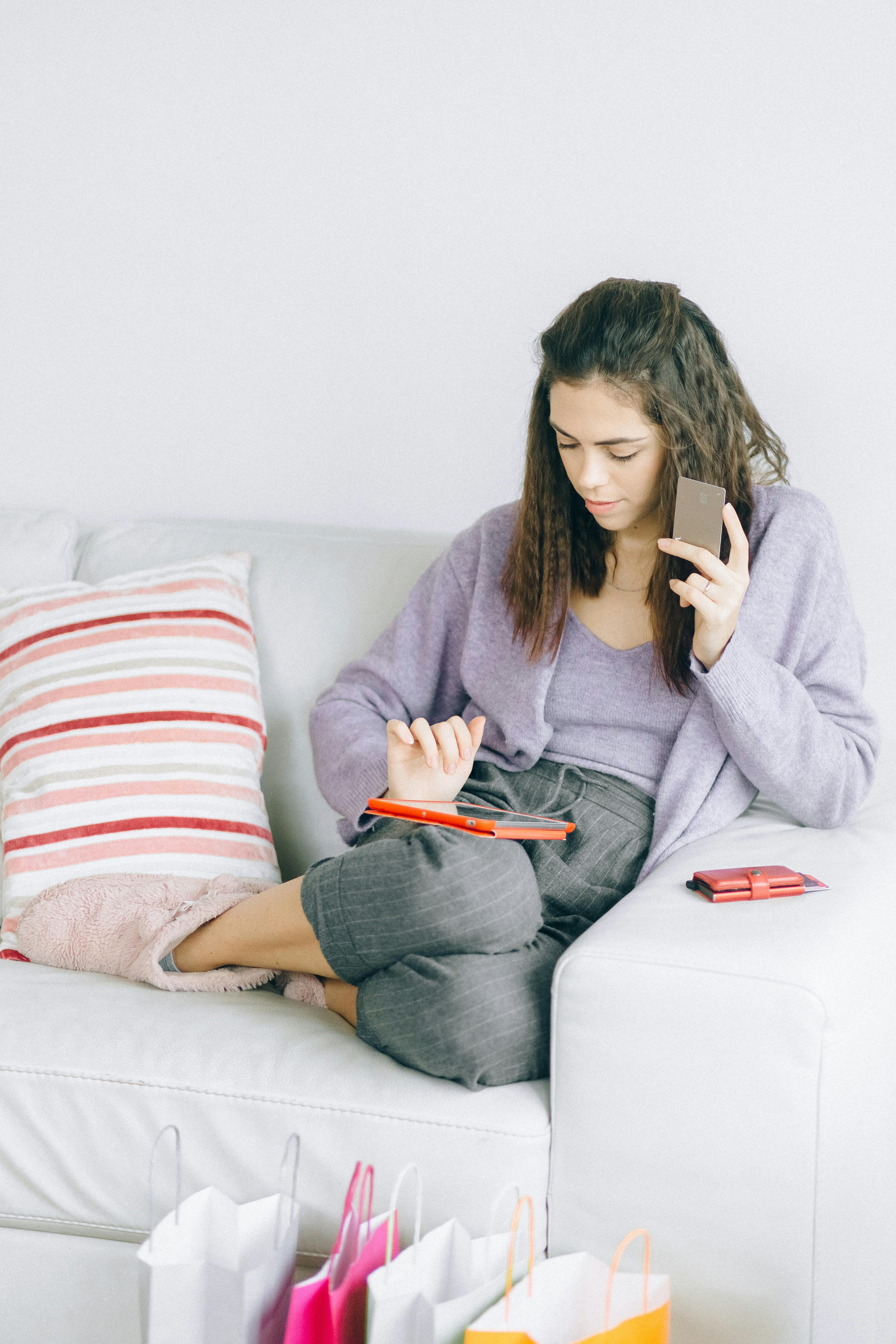 a woman using a digital tablet while holding her credit card