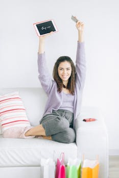 Happy woman enjoying online shopping with tablet and card, surrounded by shopping bags.