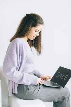 Young woman sitting indoors, using a tablet for online shopping sale.