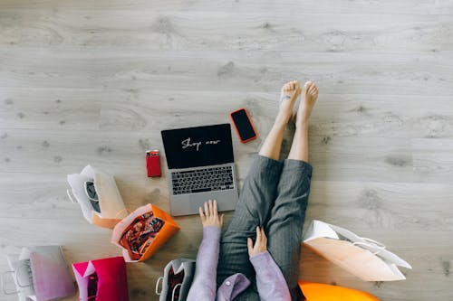 A Top Shot of a Woman Using a Laptop while Surrounded by Paper Bags