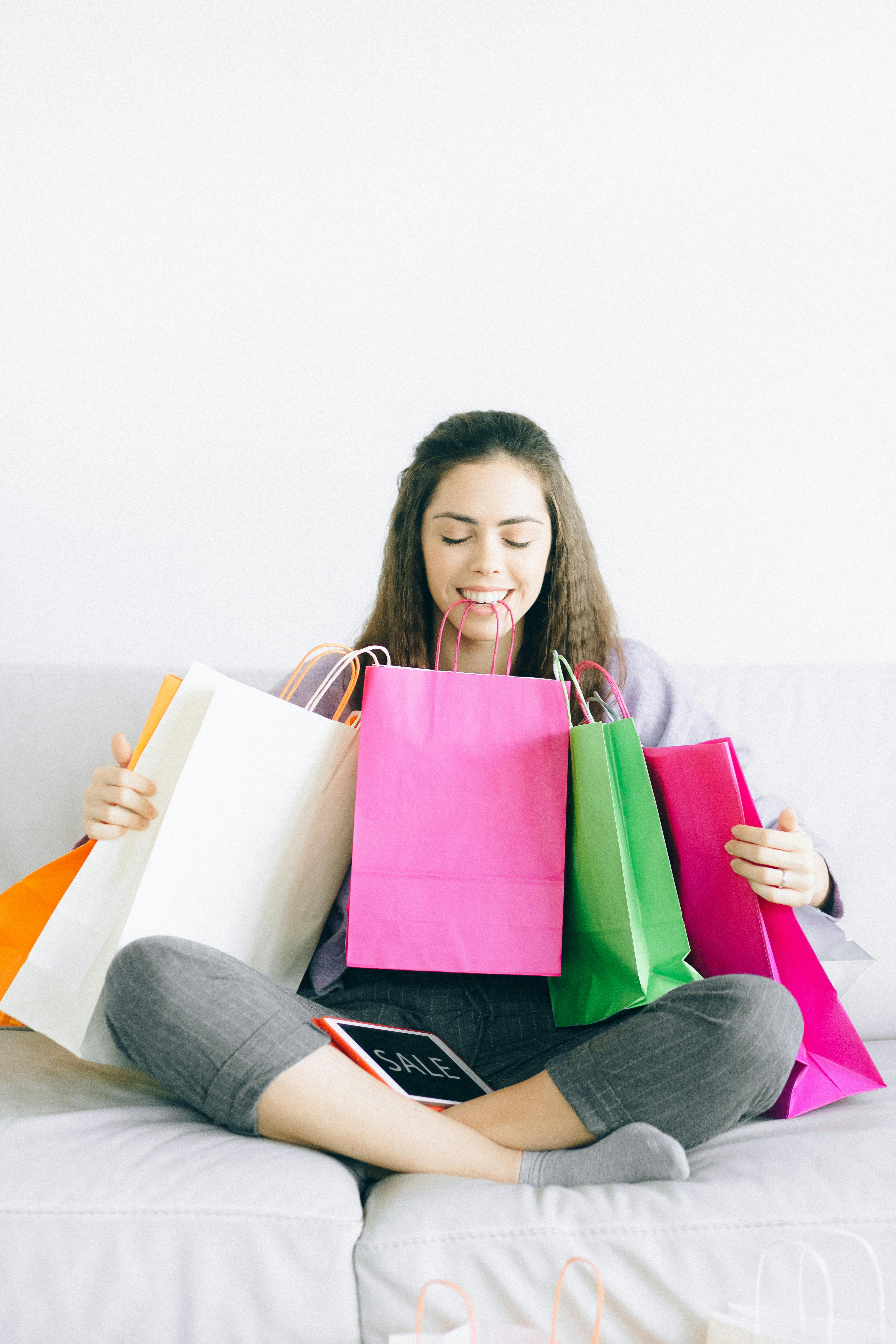 Happy woman sitting with colorful shopping bags after successful shopping spree.