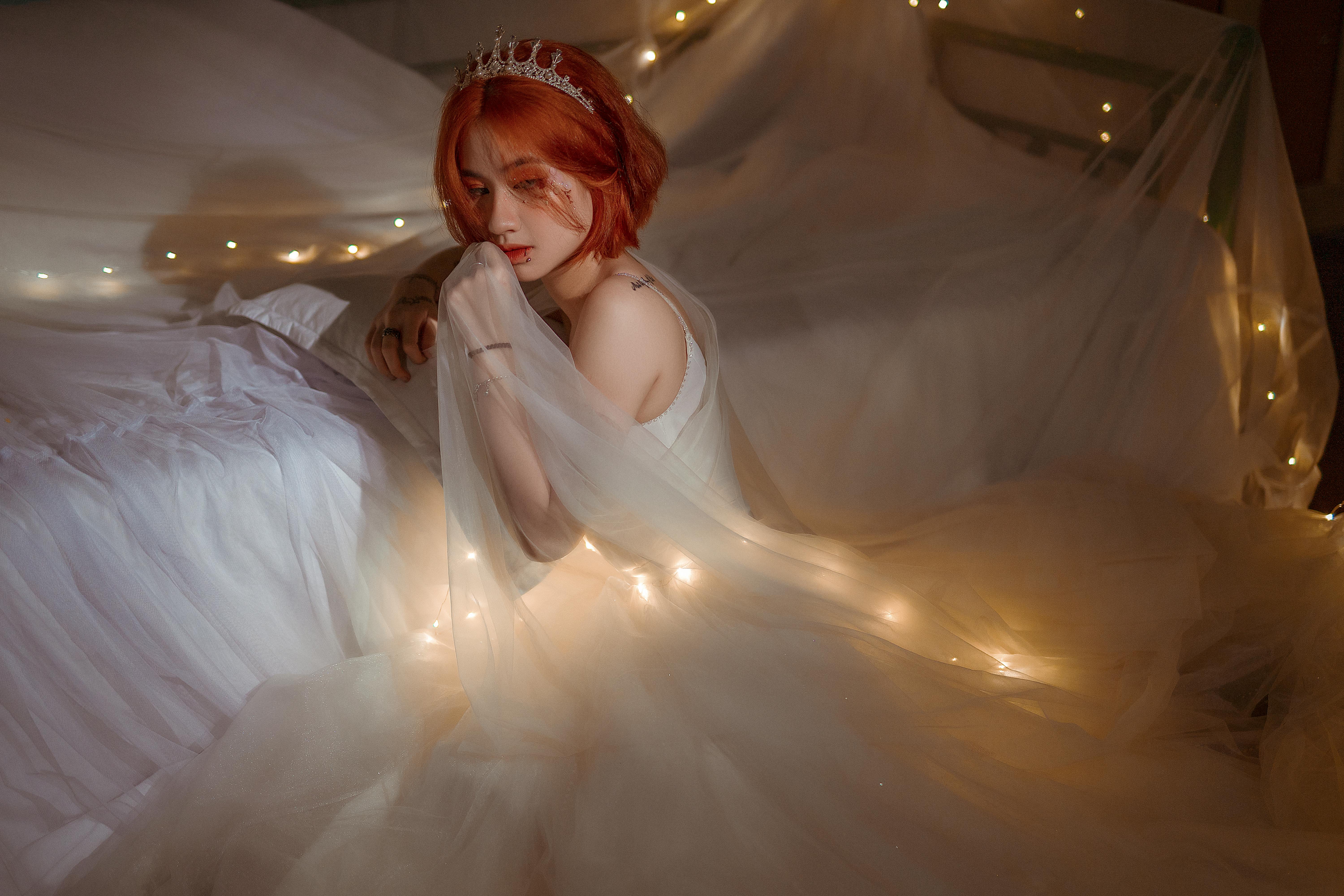 Charming Asian bride in white dress with glowing garland indoors · Free Stock Photo