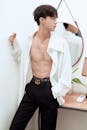 Stylish Asian man with naked torso standing in light room