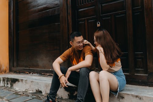 Free Happy young ethnic couple speaking and smiling while looking at each other on urban street near building Stock Photo