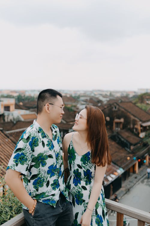 Cheerful Asian couple on terrace of town with small houses