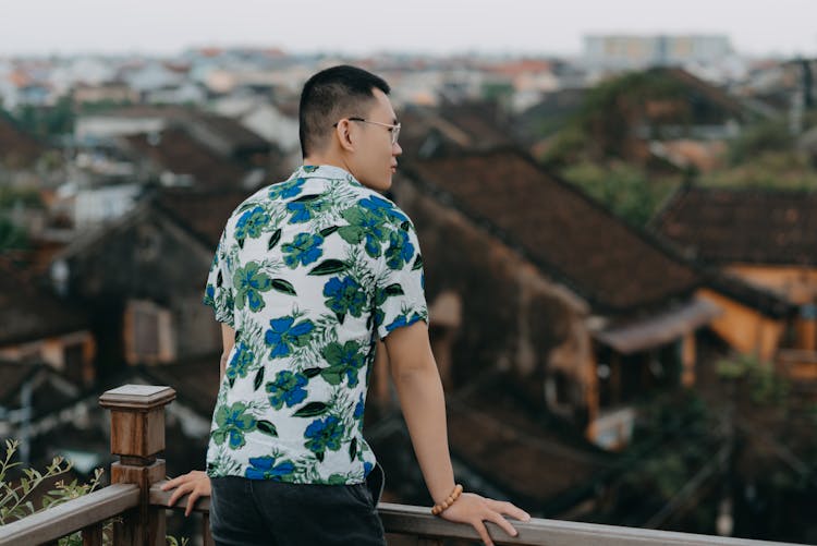 Unrecognizable Asian Man Standing On Balcony