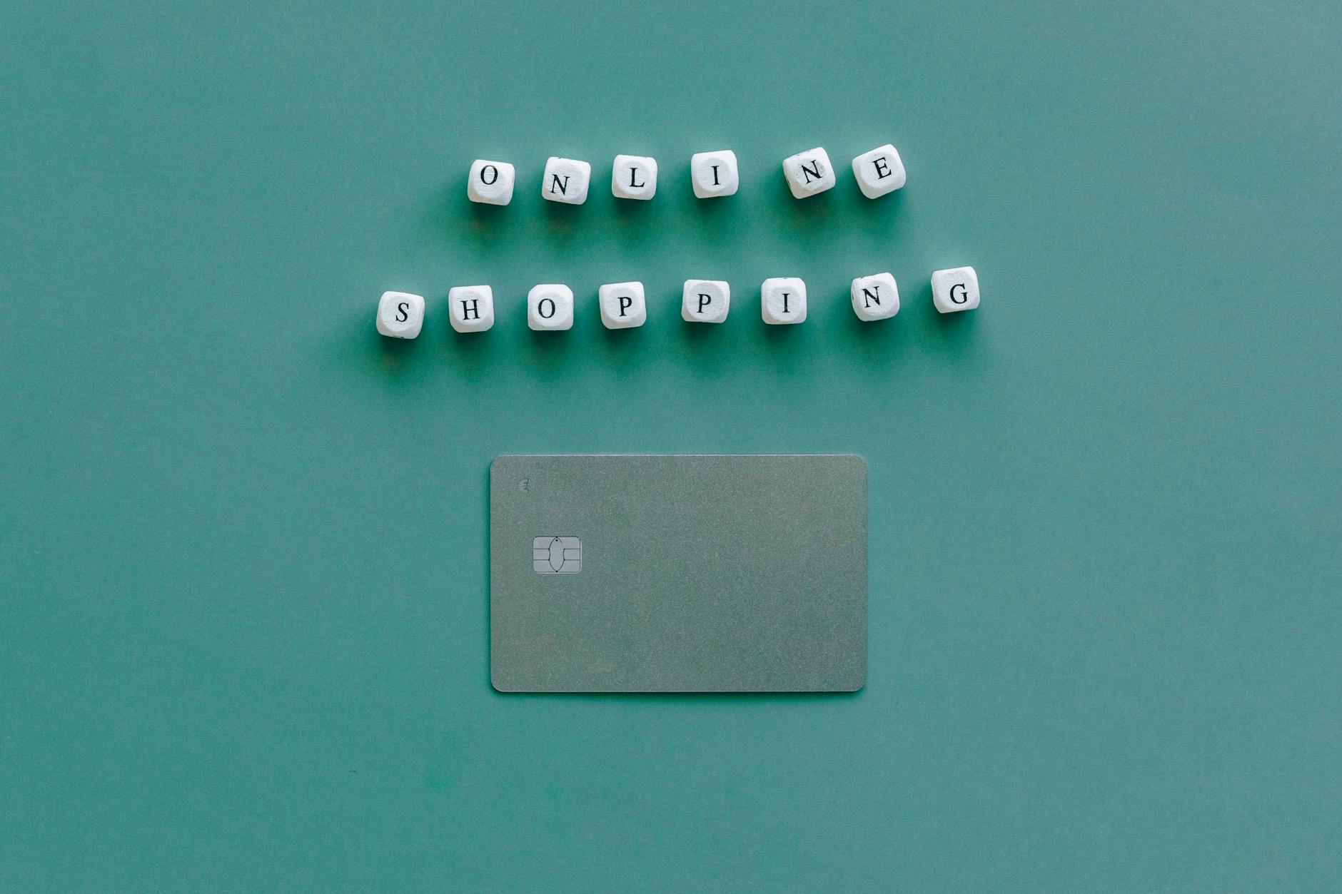 Flat lay of credit card and 'Online Shopping' text on green background, symbolizing ecommerce