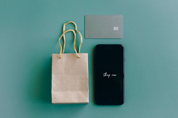 A phone, a card and a paper bag laid out on a green surface, photo by Nataliya Vaitkevich on Pexels