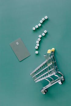 A conceptual image featuring a mini shopping cart, credit card, and letter blocks spelling 'online shopping' on a green background.