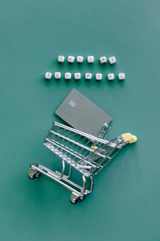 A miniature shopping cart with a credit card illustrates online shopping trends.