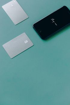 Two bank cards and a smartphone on a green surface, symbolizing online shopping.