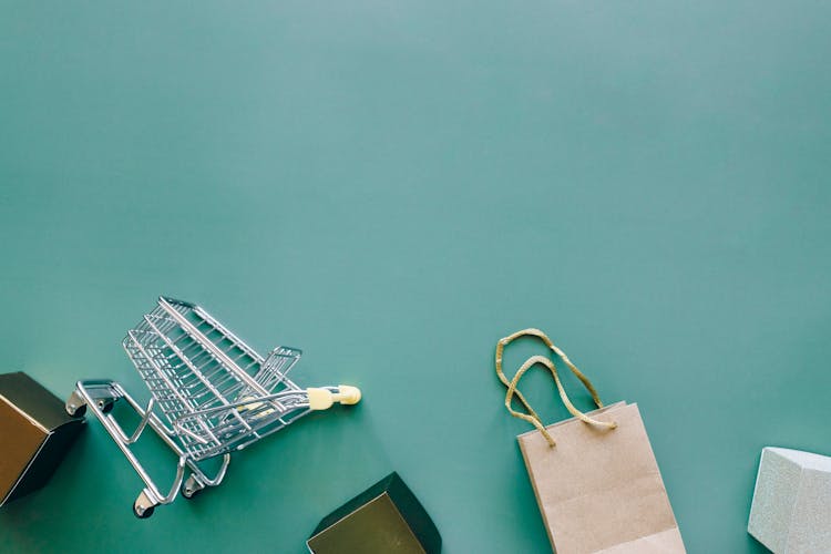 A Miniature Shopping Cart And Bag On A Blue Background