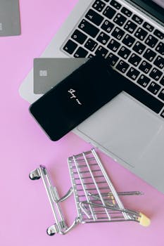 Laptop with smartphone and shopping cart, symbolizing online shopping and ecommerce.