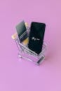 A Black Smartphone on a Miniature Shopping Cart
