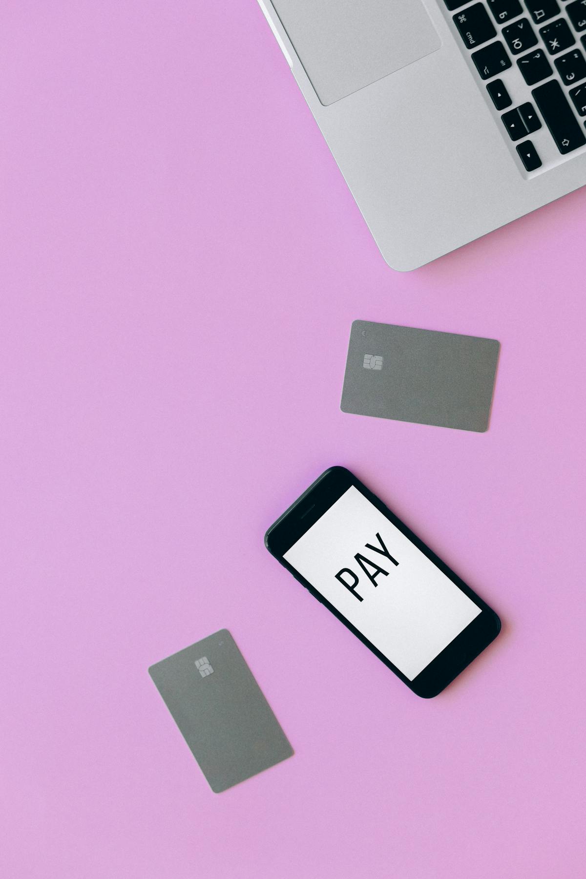 Carte di credito e smartphone disposti su una superficie rosa in piano
