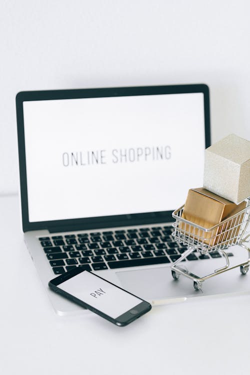Free A Miniature Shopping Cart and Smartphone on MacBook Laptop Stock Photo