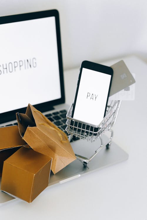 Free 
A Miniature Shopping Cart and Smartphone on MacBook Laptop Stock Photo